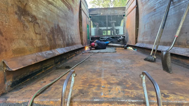 Welding inside a roll-off container floor during in-shop refurbishment at North Florida Container & Truck Repair